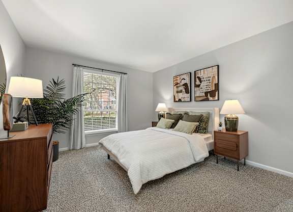 A bedroom with a bed, nightstands, and a plant.