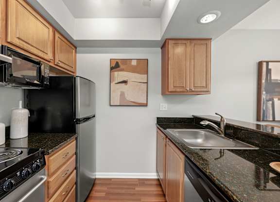 A kitchen with black granite countertops and wooden cabinets.