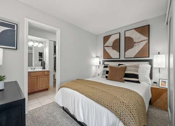 A bedroom with a bed, nightstand, and two wall art pieces.