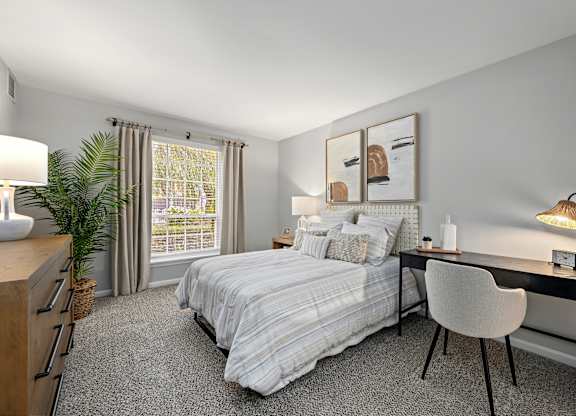 A bedroom with a bed, desk, chair, and window.