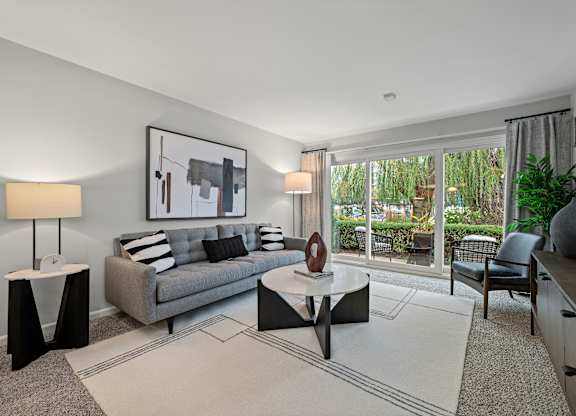 A modern living room with a grey couch, a coffee table, and a painting on the wall.