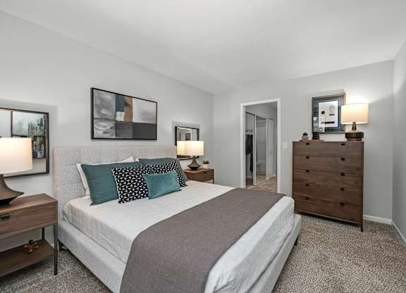 A bedroom with a bed, nightstands, and a painting on the wall.