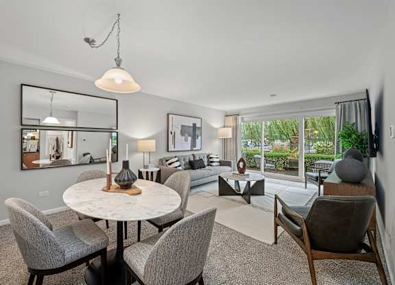 A modern dining room with a round table and grey chairs.