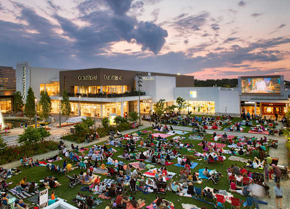 A large group of people are sitting on the grass in front of a building.