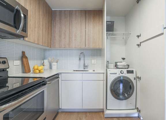A modern kitchen with a washing machine built into the wall.