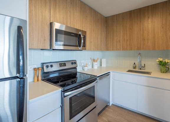 A modern kitchen with a stainless steel refrigerator, a microwave above the stove, and white cabinets.