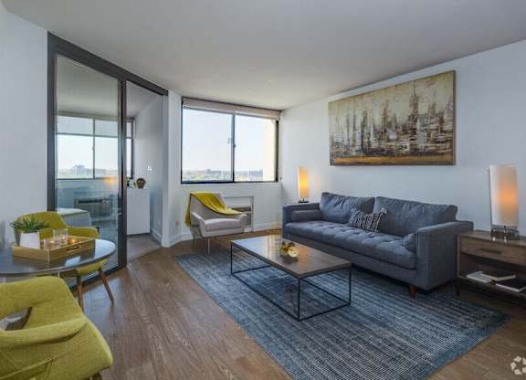 A living room with a grey couch, a yellow chair, and a painting on the wall.
