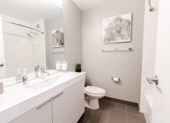 A white bathroom with a toilet, sink, and mirror.