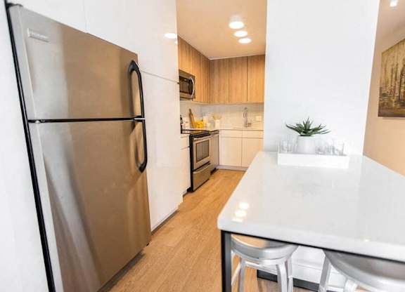 A modern kitchen with a stainless steel refrigerator and white countertops.