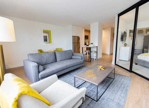 A modern living room with a grey sofa and a yellow throw.