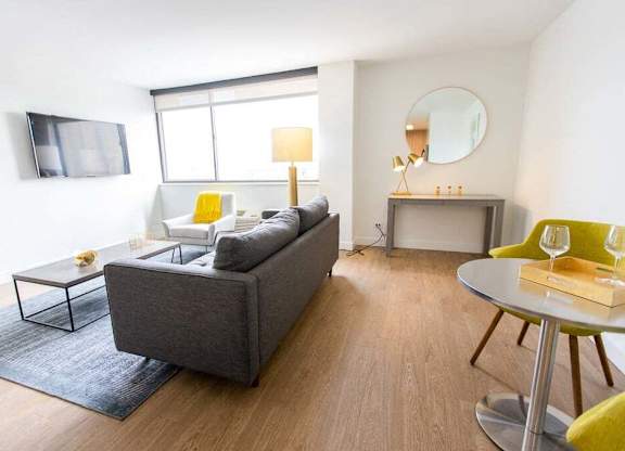 A modern living room with a grey couch, yellow chairs, and a round mirror.