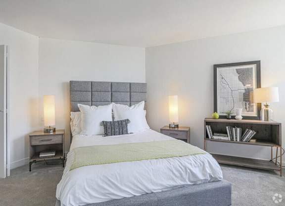 A bedroom with a large bed and a nightstand with a lamp.