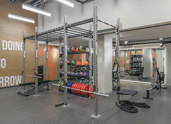 A gym with a weight rack and a wall that says "DOING".