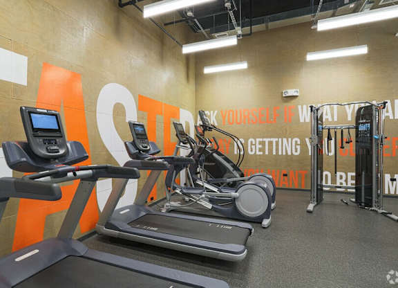 A gym with treadmills and a motivational sign on the wall.