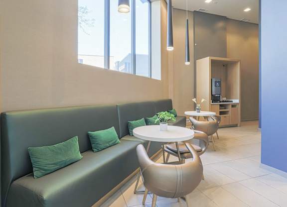 A modern waiting area with a green sofa and wooden chairs.