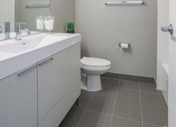 A white bathroom with a toilet, sink, and mirror.