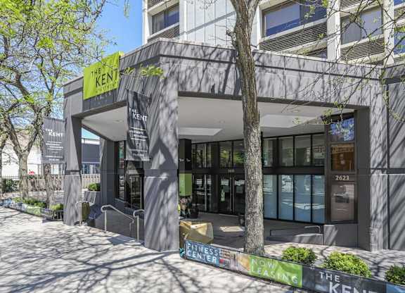 The Kent building is a modern structure with a glass facade and a tree in front.