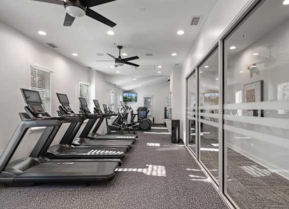 A row of treadmills are lined up in a spacious gym.