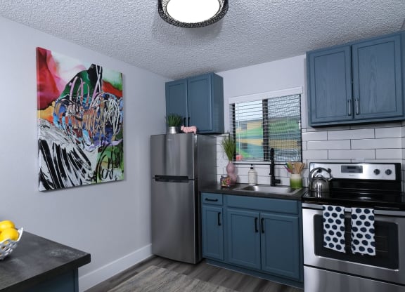 Fusion Las Vegas studios for rent in Vegas. Apartment kitchen with colorful modern painting, large window above the sink, and island with bowl of lemons.