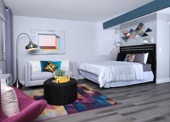 Fusion Las Vegas studio apartment sleeping and living area with large bed, geometric rug and decor, and black wicker coffee table.