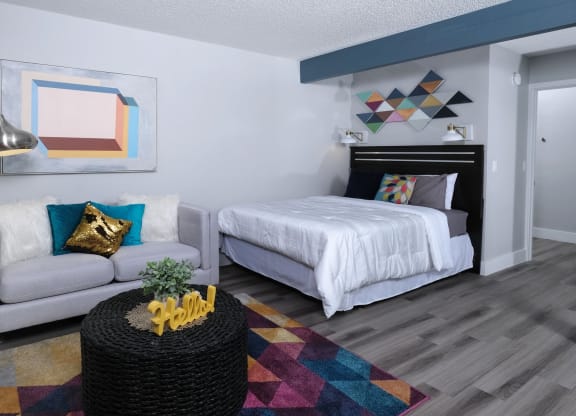 Fusion Las Vegas studio apartments Las Vegas with large bed, geometric wall hangings and paintings, and small couch with modern standing reading lamp.