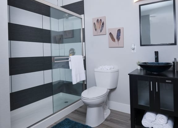 Fusion Las Vegas apartment bathroom with basin sink and black and modern black and white tiled shower with sliding glass door.
