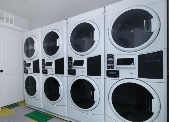 Fusion Las Vegas apartments on site laundry room with four washer dryer units and yellow, green, and grey tile floor.