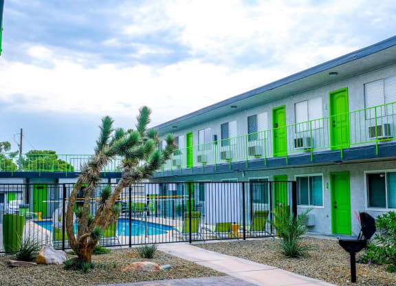 Fusion Las Vegas apartment complex 89119 with lime green doors flanking community pool and courtyard with desert landscaping and barbecue.