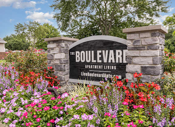 Boulevard Apartment Living sign with flowers in the foreground.