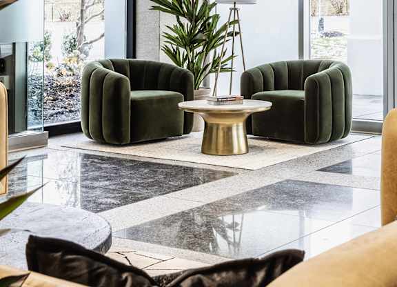 The living room is arranged with a green sofa and a round table supporting a potted plant, adding a touch of nature.