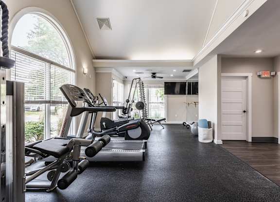 A fitness center equipped with a selection of workout equipment and large windows.