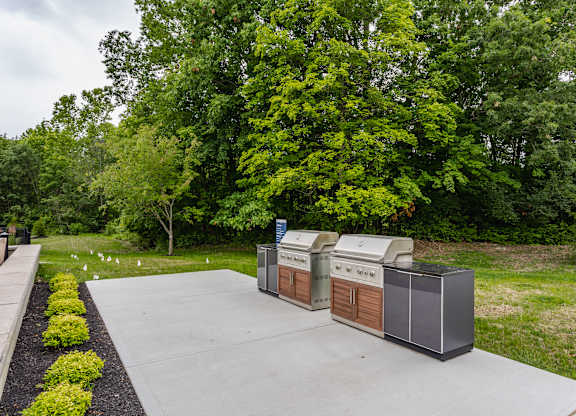 A large outdoor grill is in the middle of a concrete patio.