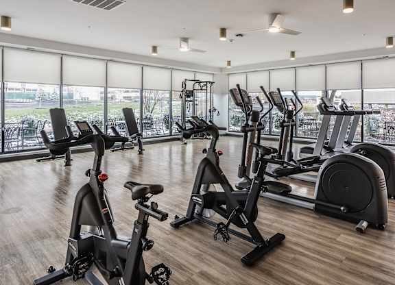 A fitness center at Altura Apartments provides residents with a row of treadmills for running and elliptical machines for low-impact exercise.