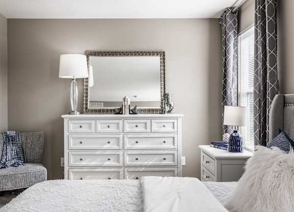 Spacious bedroom with a large dresser and mirror, perfect for personal touches