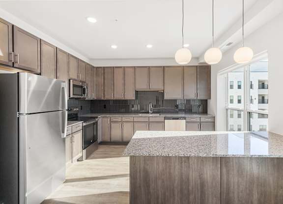 Altura Apartments, modern kitchen features a large central island with a countertop, suitable for dining or food preparation.