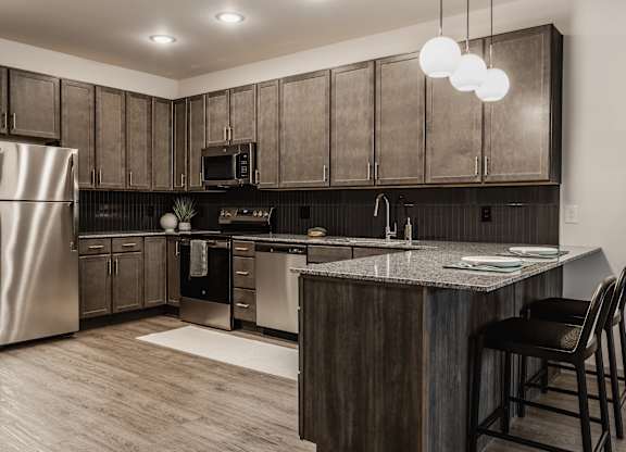 This modern kitchen showcases dark wood cabinetry complemented by stainless steel appliances, creating a sophisticated feel.