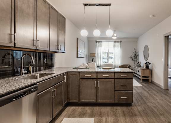 The modern kitchen design features dark wood cabinets and a practical stainless steel sink with a gooseneck faucet.