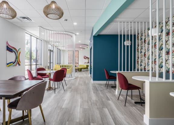 Co-working lounges at Madamore Apartments with tables and chairs, stylish decor, and windows.