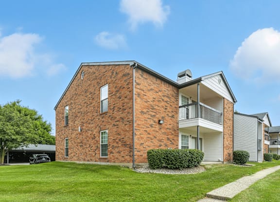 A brick house with a white garage door and a white house next to it.