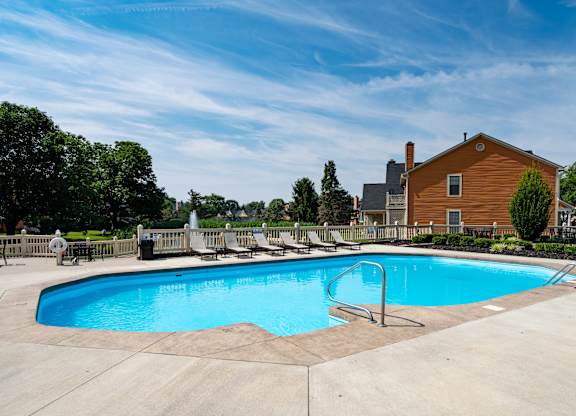 A large outdoor swimming pool with a slide and a house in the background.
