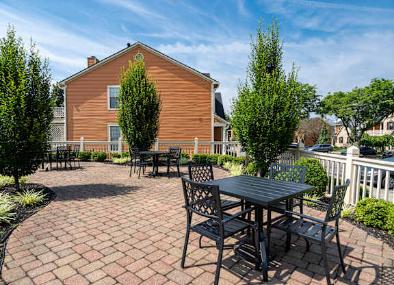 A wooden house with a patio and chairs.