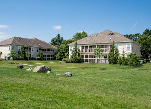 Two houses with a green lawn in front.