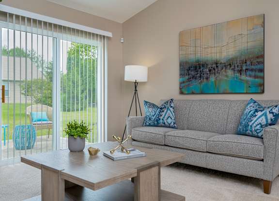 A living room with a grey couch, a wooden table, and a painting on the wall.