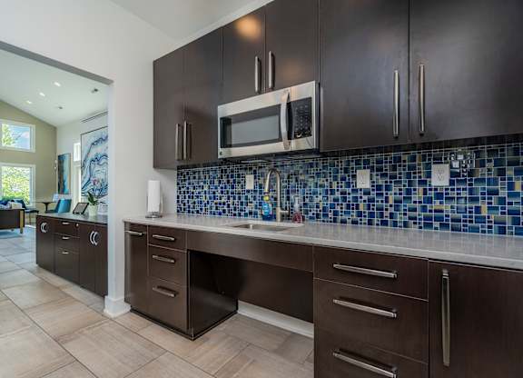 A kitchen with dark brown cabinets and a blue tile backsplash.