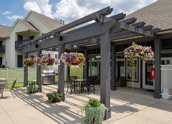 A patio with a pergola and flowers in pots.