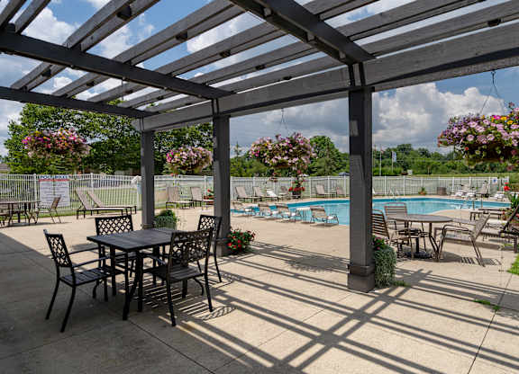 A patio with a table and chairs overlooking a pool.