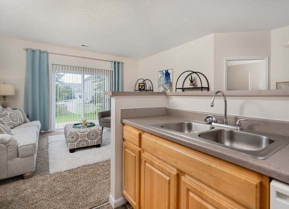 A kitchen with a sink and a window with curtains.