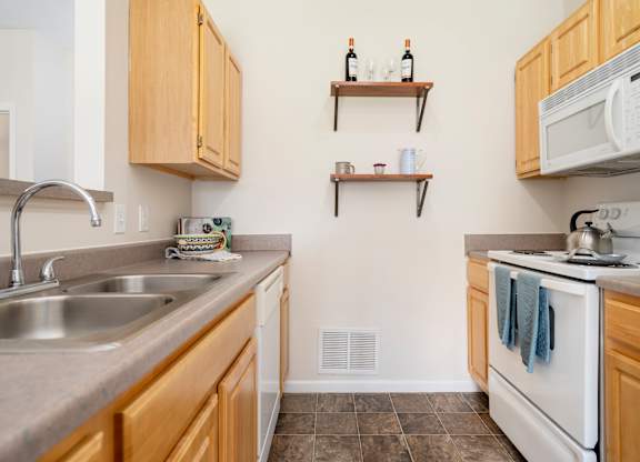 A kitchen with a white oven and a white microwave.