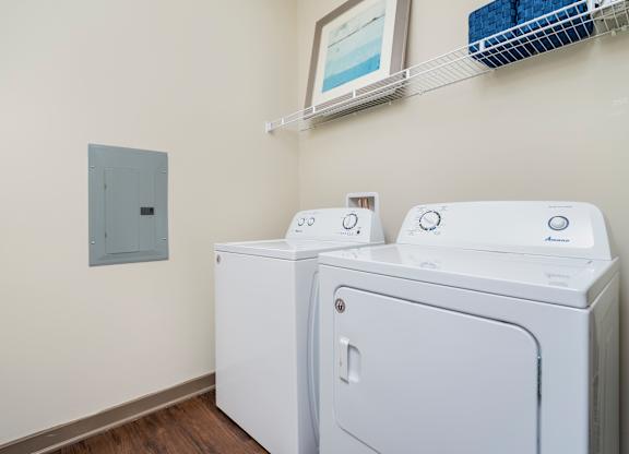 A wall-mounted electrical outlet is next to two washing machines.