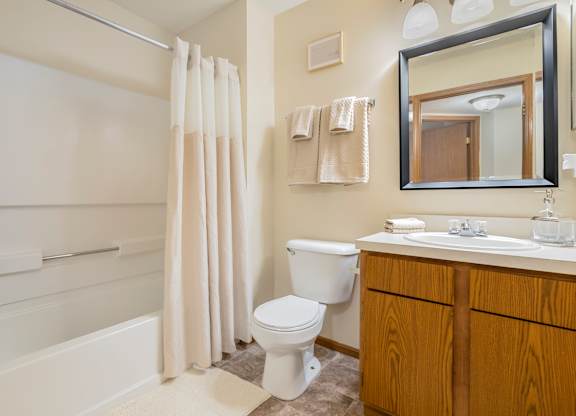 A white toilet sits in a bathroom next to a white sink.